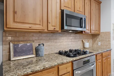 a kitchen with granite countertop a stove top oven microwave and cabinets