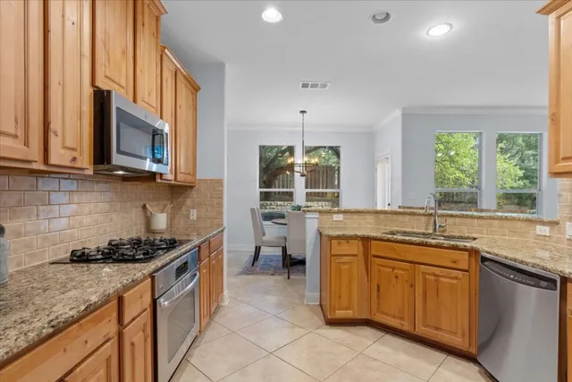 a kitchen with stainless steel appliances granite countertop a stove a sink and a microwave