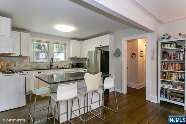 24 Robinhood Avenue Closter, NJ 07624 - Photo 7 of 20 a kitchen with stainless steel appliances granite countertop a stove a refrigerator a dining table and chairs with wooden floor