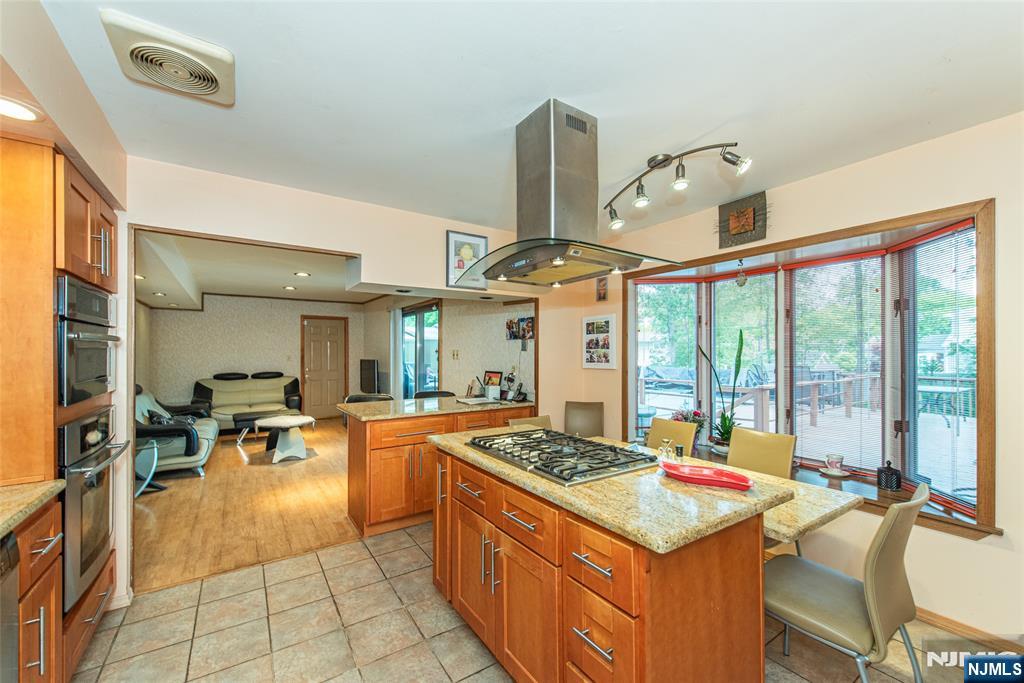12 Abbott Road Wayne, NJ 07470 - Photo 14 of 49 a open kitchen with stainless steel appliances granite countertop a stove top oven a dining table and chairs with the view of living room
