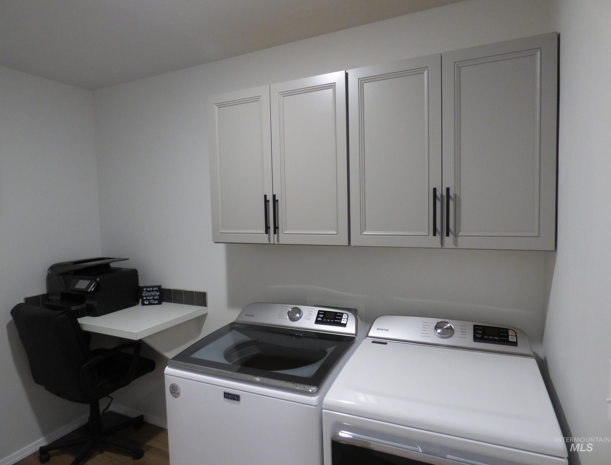 2708 East Buckaroo Drive Kuna, ID 83634 - Photo 25 of 48 Laundry area featuring overhead cabinetry, a built-in desk, and a tiled backsplash