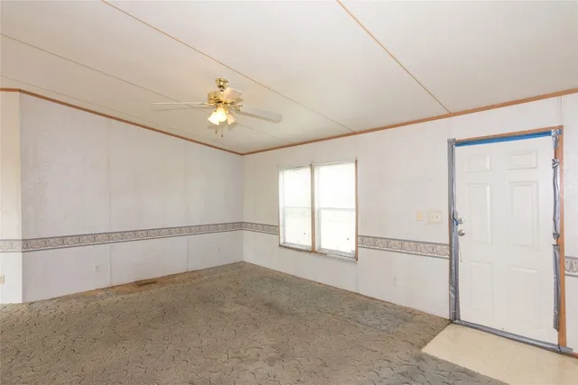 an empty room with windows and chandelier fan