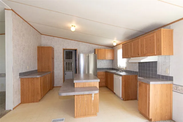 a open kitchen with stainless steel appliances granite countertop a refrigerator a sink dishwasher a stove and a dining table with the view of living room