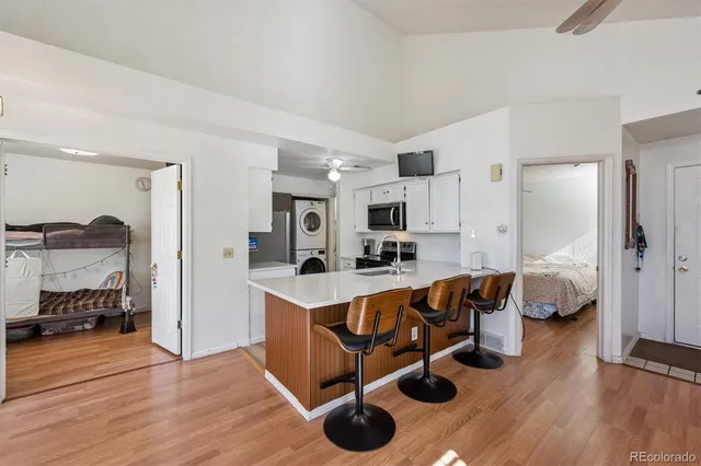 a open kitchen with stainless steel appliances granite countertop a stove top oven a sink dishwasher a dining table and chairs with wooden floor