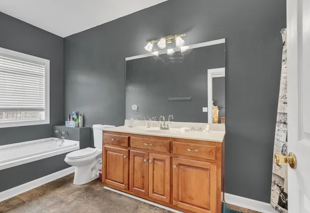 a spacious bathroom with a granite countertop toilet a sink and a bathtub