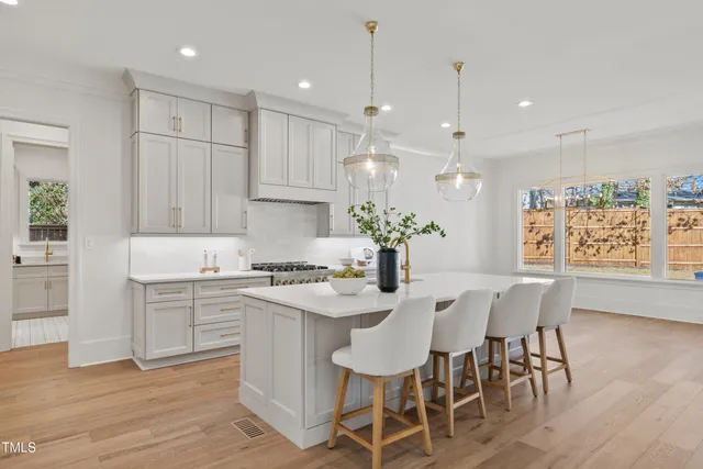 a kitchen with white cabinets stainless steel appliances dining table and chair