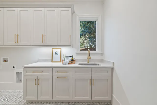 a kitchen with white cabinets and sink