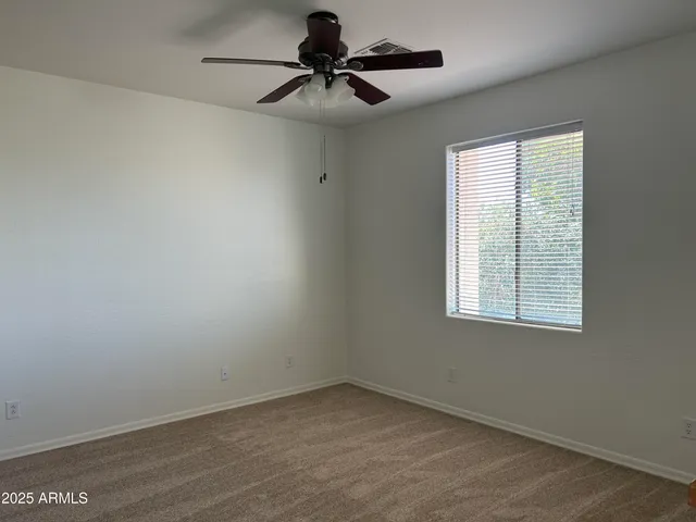 an empty room with a window and a fan
