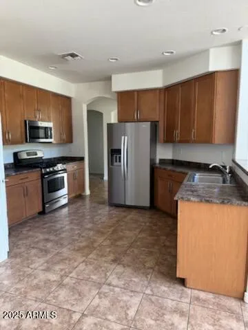 a kitchen with stainless steel appliances granite countertop a stove a refrigerator a sink a microwave and island