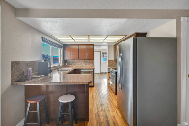 10 North Main Street Centerfield, UT 84622 - Photo 11 of 52 Kitchen with stainless steel appliances, brown cabinetry, light wood finished floors, decorative backsplash, and a peninsula