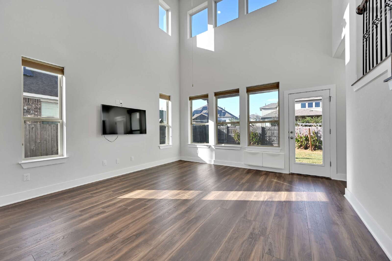 4420 Kings Cross Road Pflugerville, TX 78660 - Photo 2 of 25 Rich wood-look flooring and soaring double-height walls frame this sunlit, airy living area.