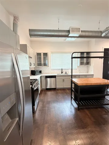 a kitchen with stainless steel appliances granite countertop a refrigerator a stove and a sink