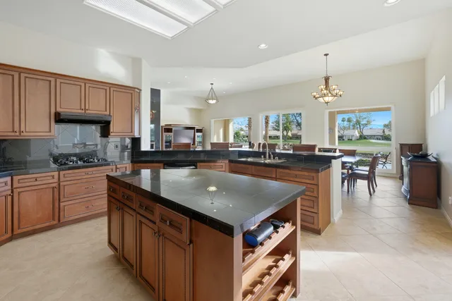 a kitchen with kitchen island granite countertop a sink a counter top space and stainless steel appliances