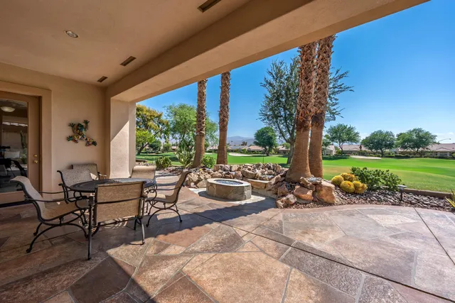 a view of a patio with table and chairs potted plants and palm tree
