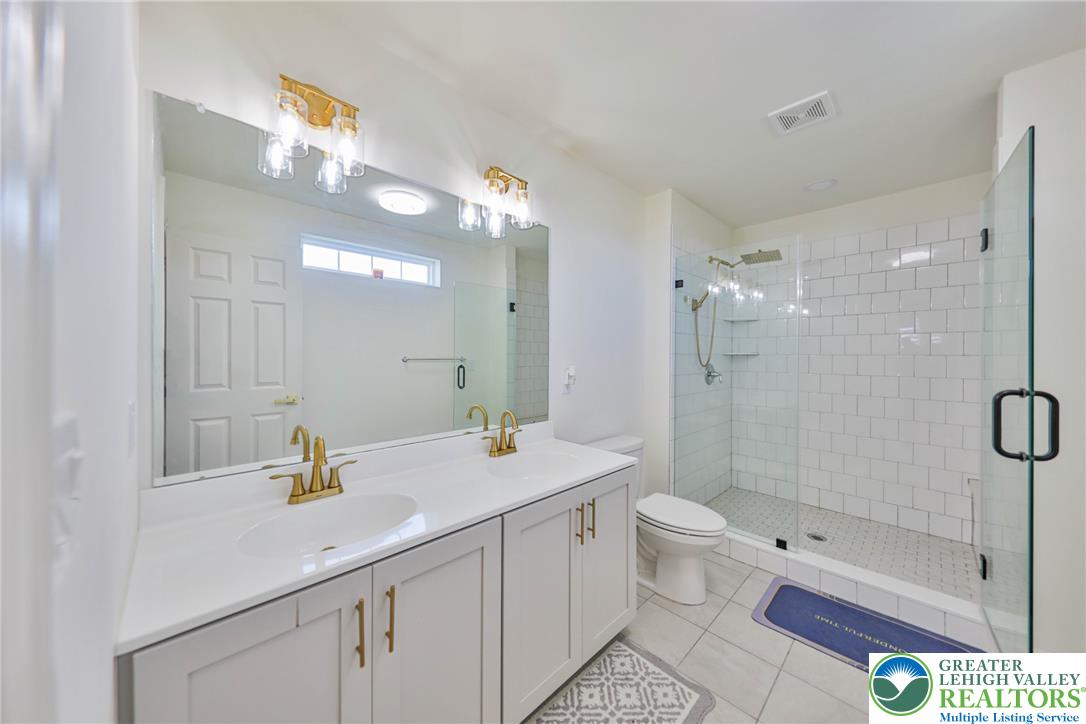 1105 Meco Road Easton, PA 18040 - Photo 52 of 100 A spacious double vanity and a glass-enclosed walk-in shower elevate this modern bathroom.