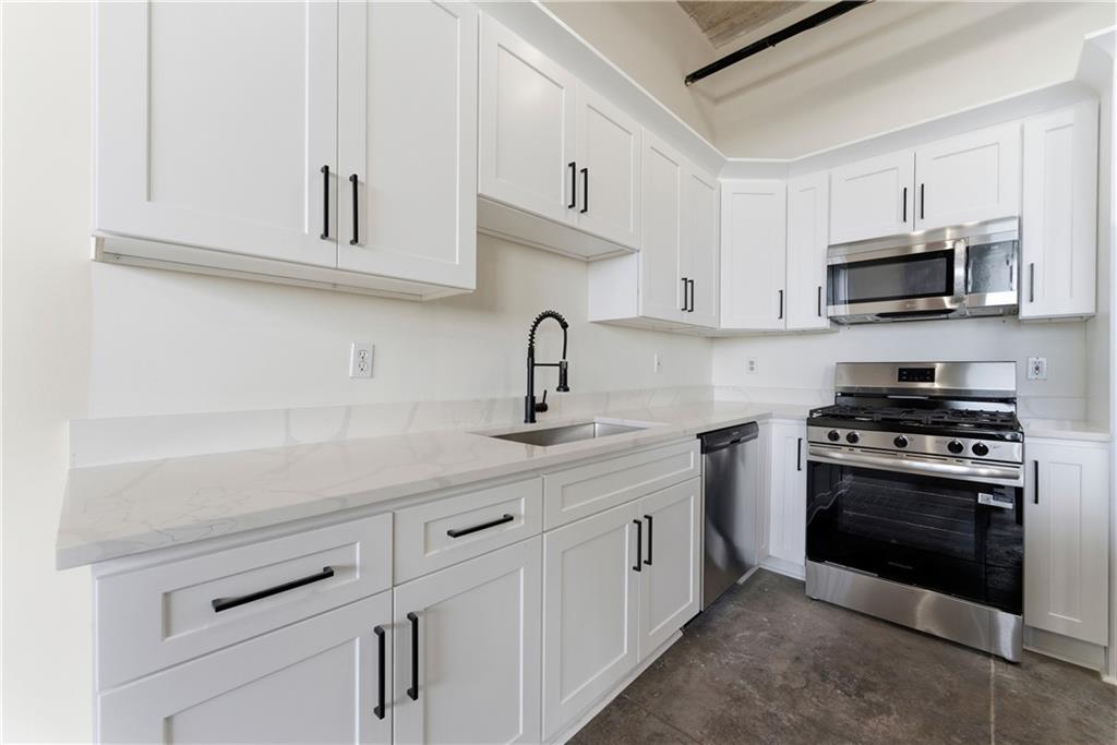 505 Whitehall Street Southwest, Unit 307 Atlanta, GA 30303 - Photo 3 of 35 a kitchen with stainless steel appliances granite countertop white cabinets a sink and dishwasher