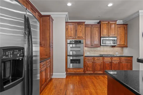 a kitchen with stainless steel appliances granite countertop a refrigerator and wooden cabinets