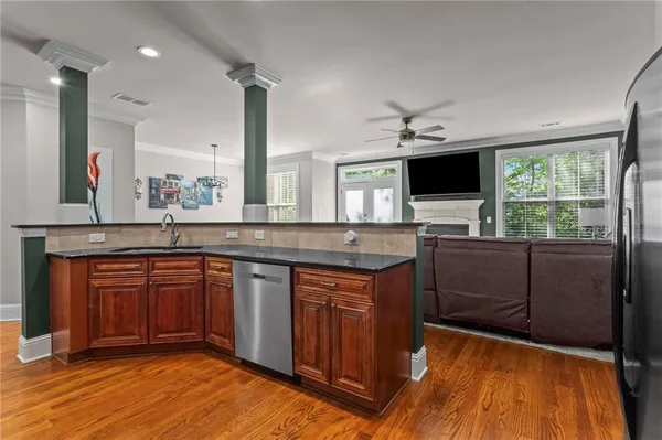 a kitchen with stainless steel appliances granite countertop wooden cabinets a sink a stove a dining table and chairs