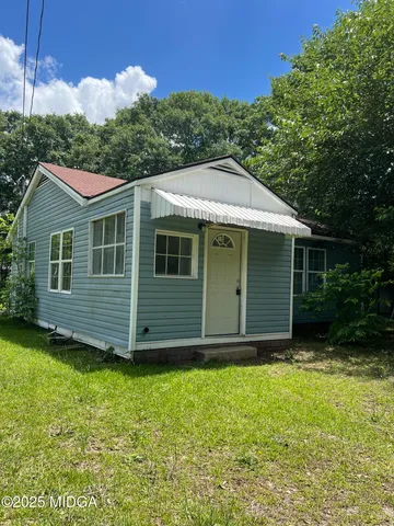 a view of a house with a yard plants and large tree