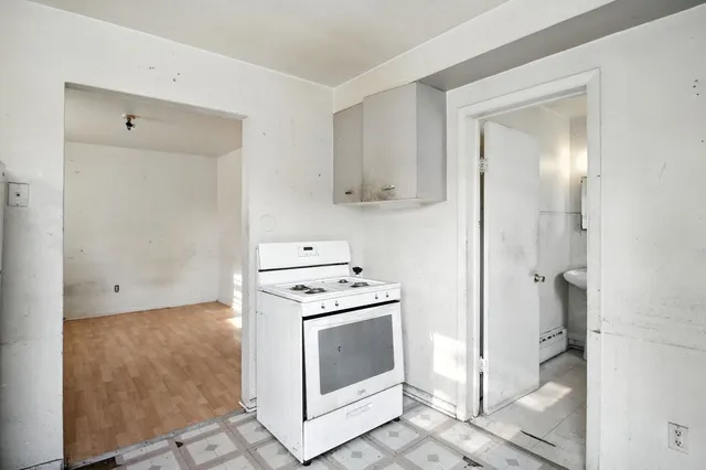an empty room with a chandelier fan and wooden floor