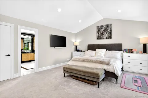 a spacious bedroom with a bed and a flat screen tv