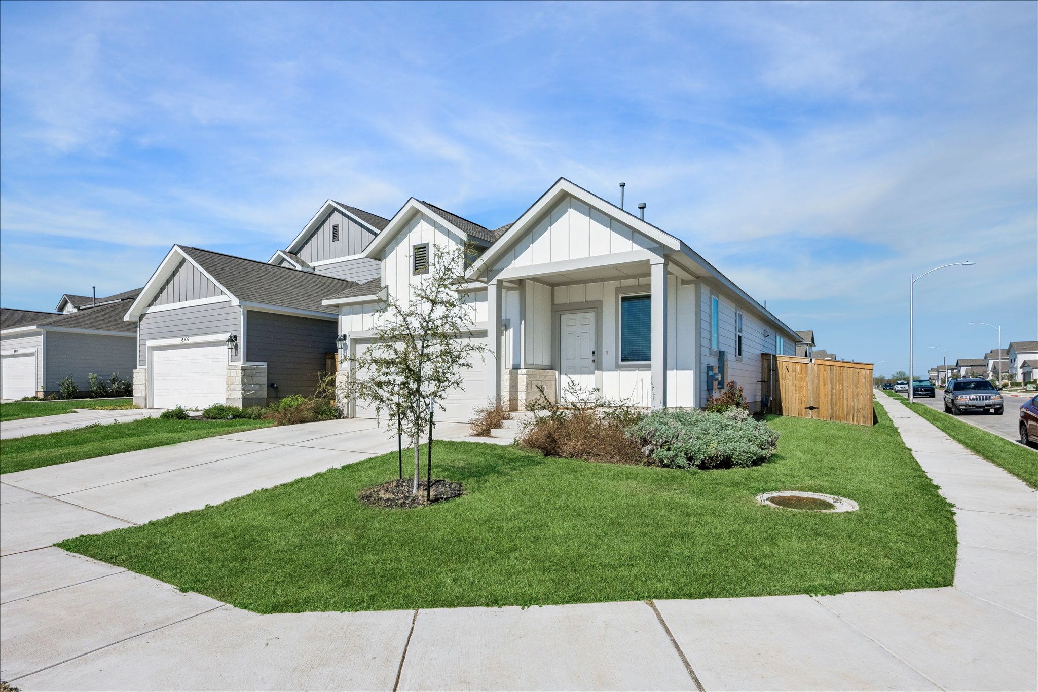 View of front of property with board and batten siding, concrete driveway, a front lawn, and an attached garage