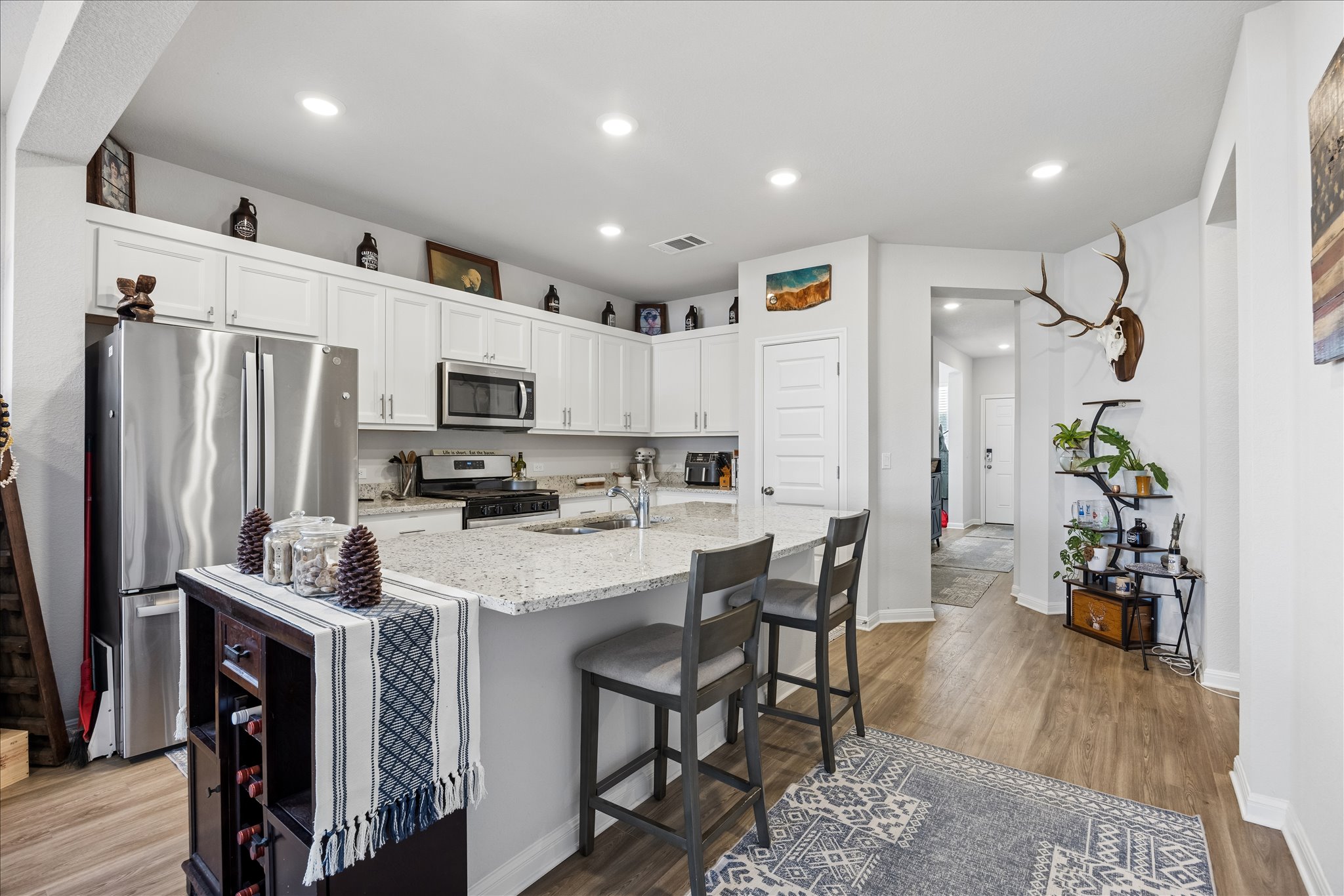 8300 Augeron Drive Austin, TX 78747 - Photo 8 of 16 Kitchen with stainless steel appliances, white cabinetry, dark wood-style floors, recessed lighting, and a kitchen island with sink