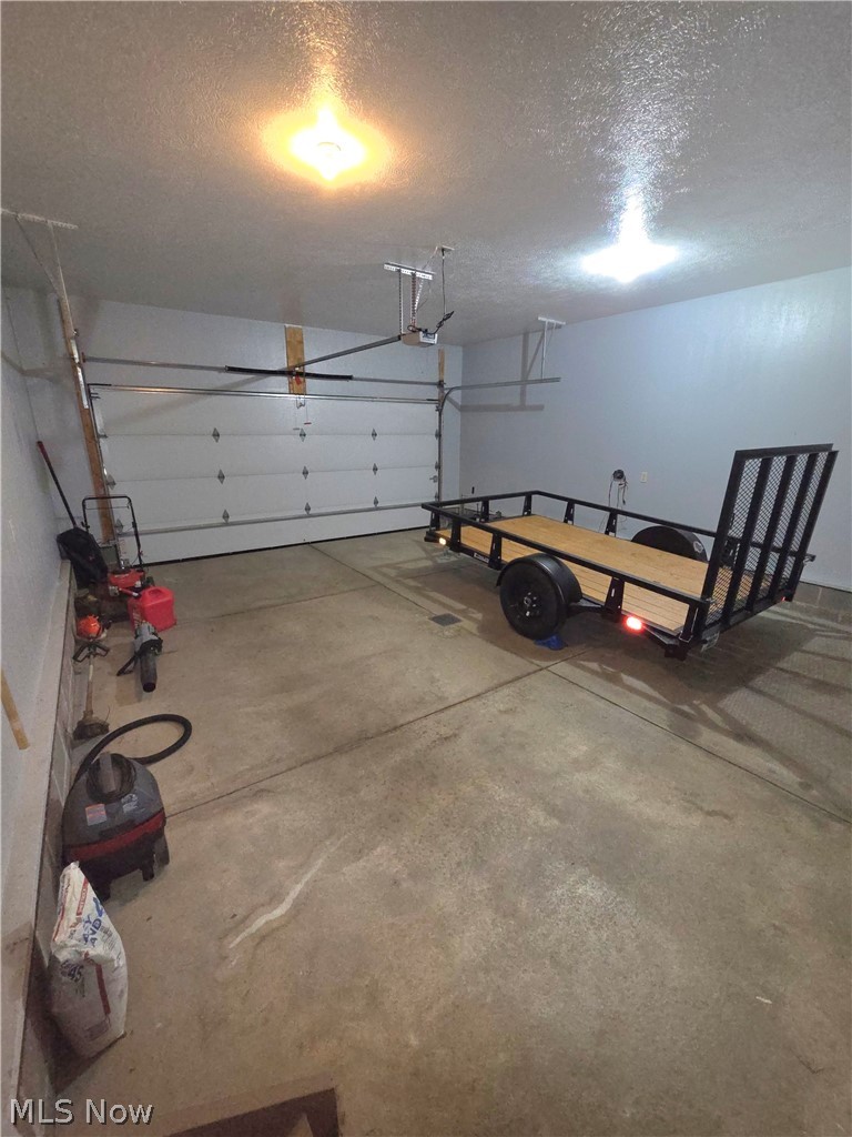 202 Home Street Rittman, OH 44270 - Photo 4 of 23 Garage space featuring a paneled overhead door, concrete flooring, and ceiling-mounted lighting