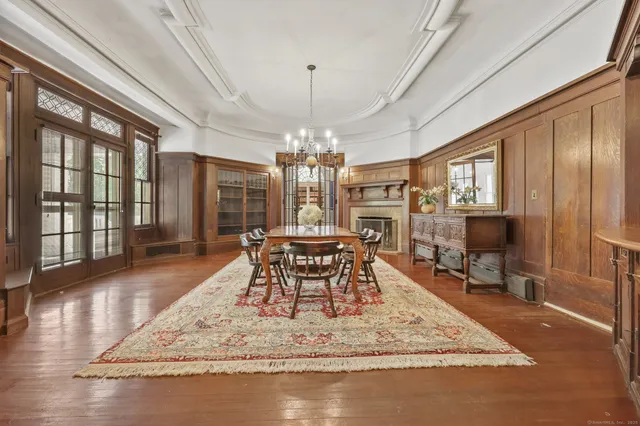 a dining room with wooden floor a chandelier a wooden table and chairs