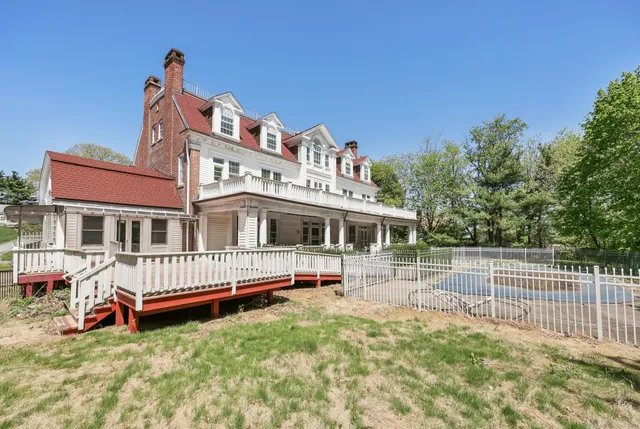 a front view of a house with a garden and lake view