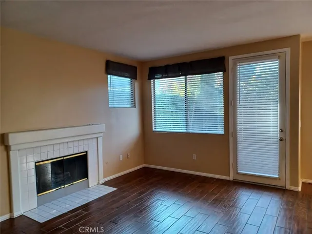 an empty room with wooden floor fireplace and windows