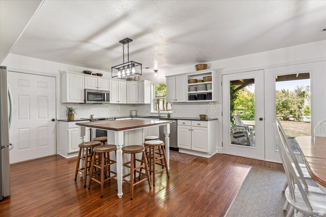 246 West Mount Charm Road Toquerville, UT 84774 - Photo 14 of 70 Kitchen with a breakfast bar, stainless steel appliances, decorative light fixtures, dark wood-type flooring, and white cabinetry