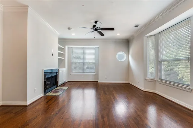 an empty room with wooden floor fan and windows