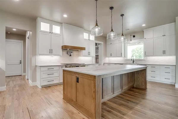 a kitchen with kitchen island granite countertop a sink cabinets and wooden floor