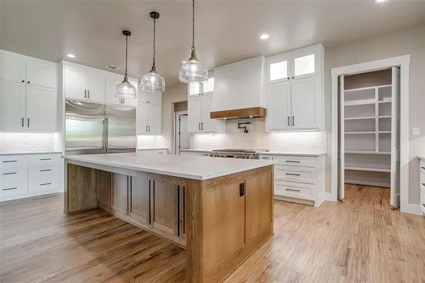 a large kitchen with stainless steel appliances kitchen island a large counter top and a wooden floors