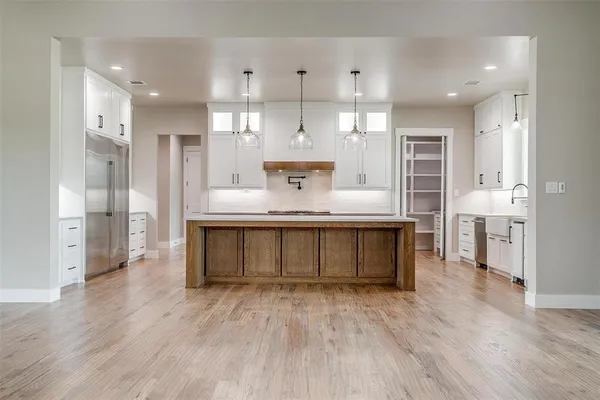 a large kitchen with stainless steel appliances a large counter top a sink a stove and a refrigerator