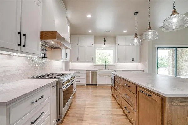 a kitchen with stainless steel appliances granite countertop a sink a stove and a wooden floors