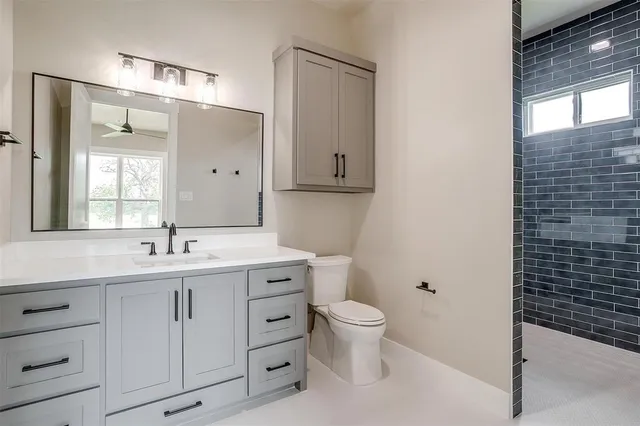 a bathroom with a granite countertop sink toilet and mirror