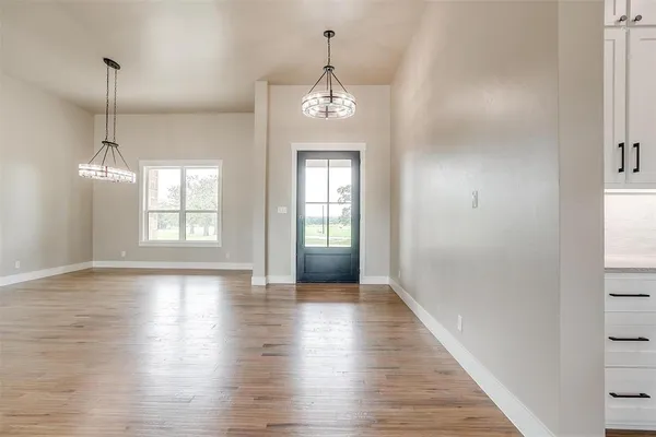 a view of an empty room with wooden floor and a kitchen