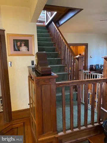 a view of a hallway with wooden floor and stairs