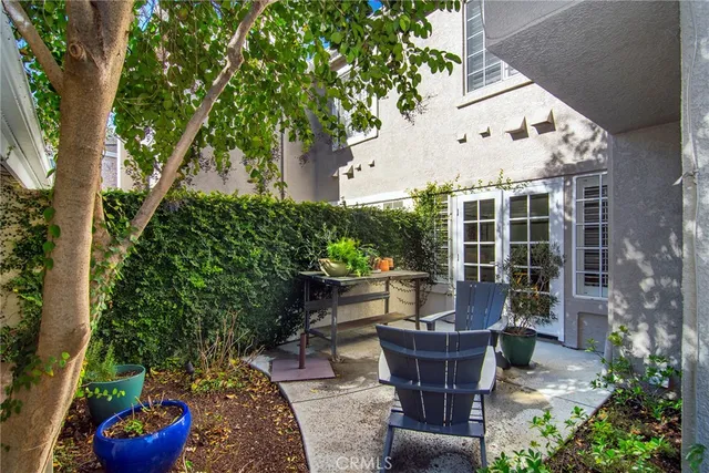 a view of a patio with table and chairs potted plants and large tree