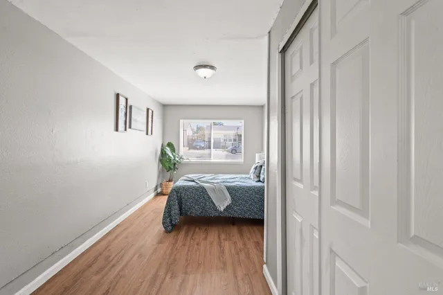 a view of a hallway with wooden floor and a bathroom