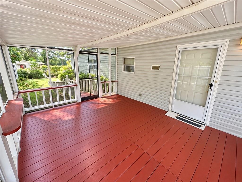 28 Southfork Road Eufaula, AL 36027 - Photo 3 of 20 Screened porch featuring a red-stained wood deck, white vinyl siding, and white aluminum ceiling