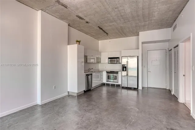 a view of a kitchen with refrigerator and chairs