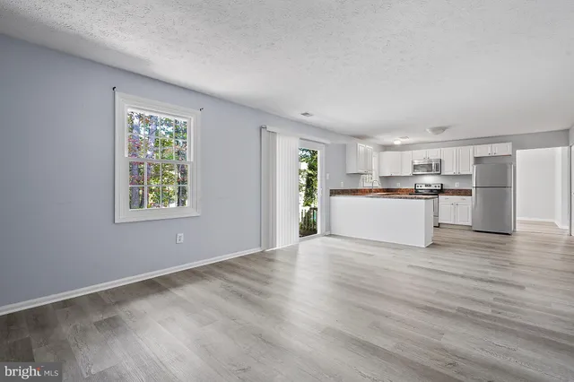 a view of a kitchen with a sink wooden cabinets and a window