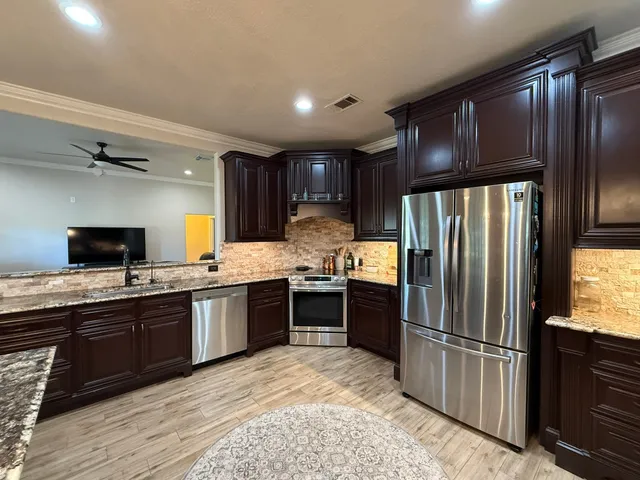 a kitchen with stainless steel appliances granite countertop a refrigerator stove and sink
