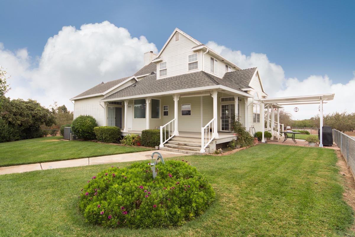a white house with a large pool and lawn chairs next to a yard