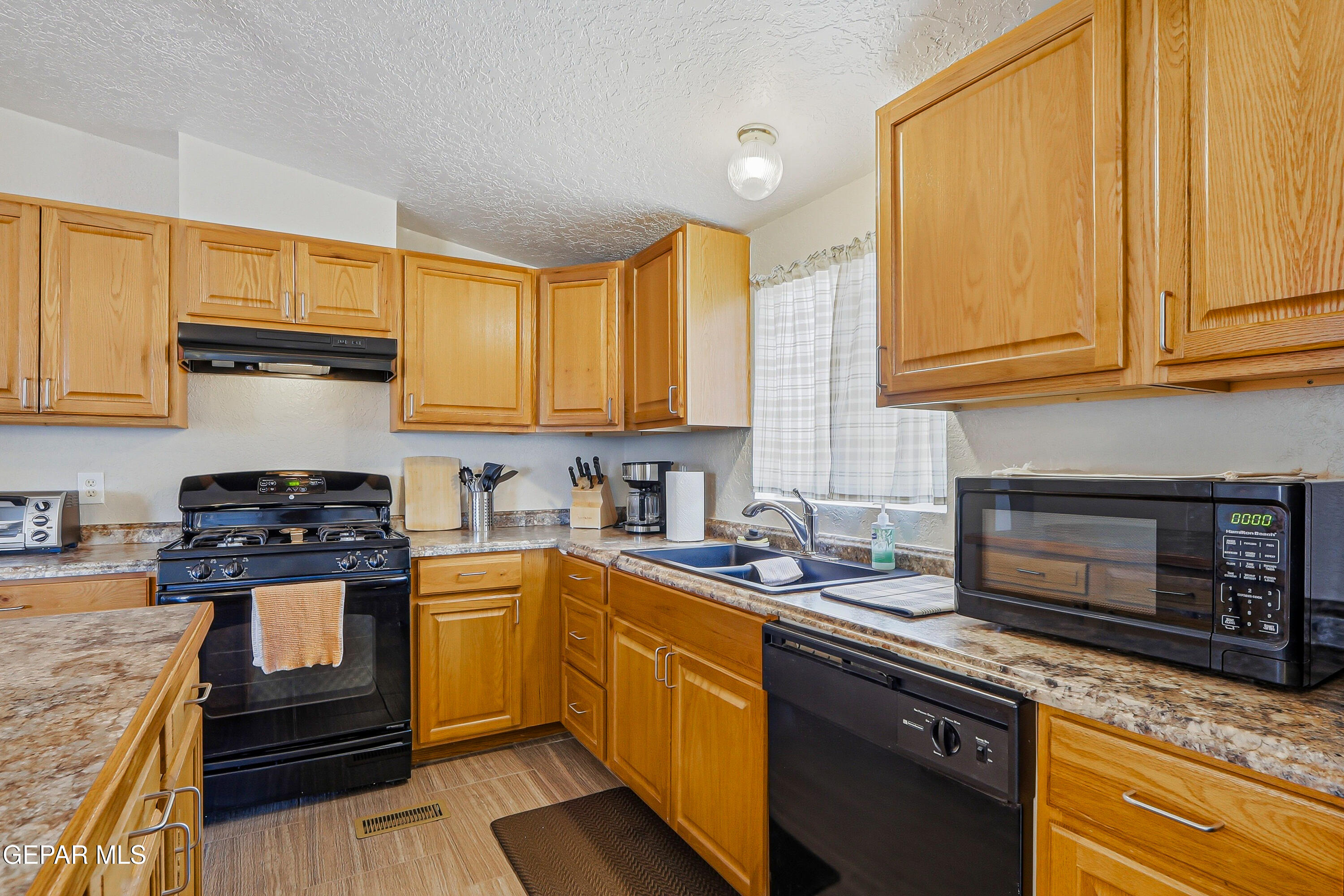 2901 Cook Street Truth or Consequences, NM 87901 - Photo 7 of 31 a kitchen with stainless steel appliances granite countertop a stove a sink dishwasher and a microwave oven with cabinets