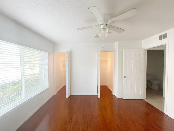 a view of an empty room with wooden floor and a window