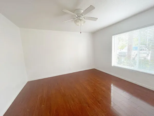 an empty room with a window and a fan
